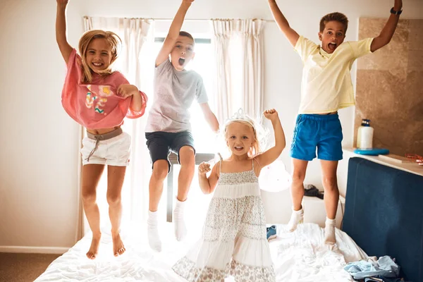 Four little monkeys jumping on the bed. Portrait of little siblings jumping on a bed at home