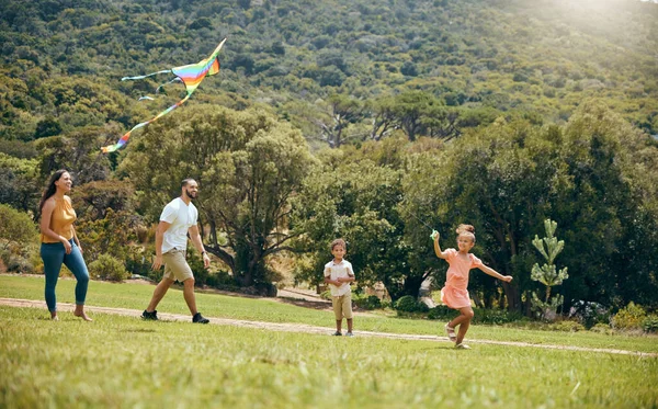Kite, parents and children being happy in nature and playful in quality time together, on weekend and on vacation. Family, mother and father with kids, happiness or fun with flying toy, joy or summer.