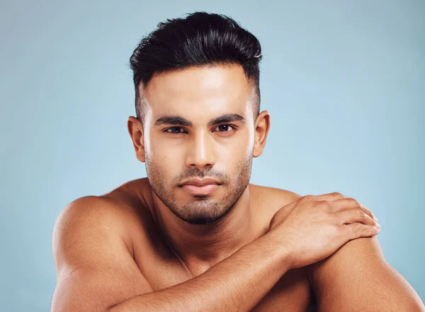 Beauty, skincare and face portrait of man on blue studio background. Health, dermatology and wellness of male model from India with serious facial expression, beard hair or glowing and healthy skin