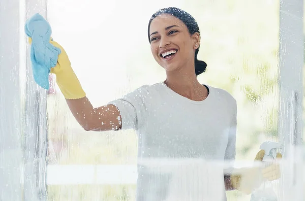 Cleaning, glass and shower door with woman in bathroom for hygiene, bacteria and sanitize. Smile, service and washing with girl and cleaner product at home for housekeeping, germs and disinfection.