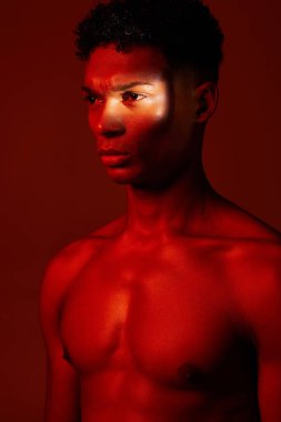 Red, light and body, beauty and man isolated on studio background. Neon light, serious facial expression and male model from Brazil thinking, lost in thought or focus on fitness, health and wellness clipart