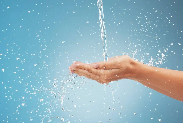 Woman, hands and water splash on blue background in studio for healthcare, cleaning and washing hands. Zoom, model and pouring fresh faucet liquid in earth sustainability, conservation and protection.