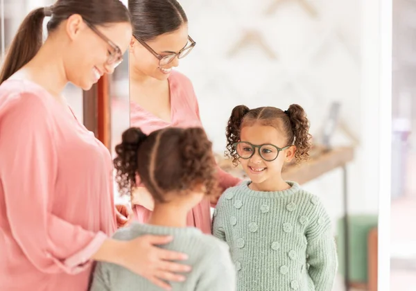 Family, optics store and shopping with mother and child happy with glasses choice in mirror for eye care, vision and optical health. Woman and girl customer with lens or frame decision in retail shop.