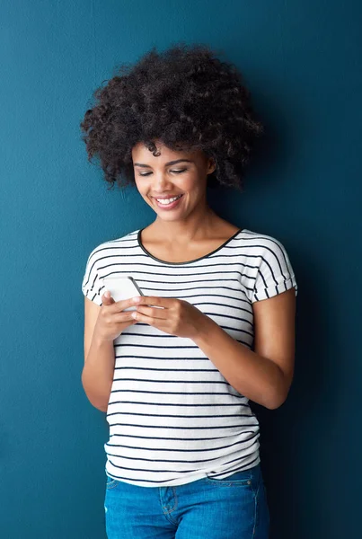 stock image Theres so much buzzing online today. Studio shot of an attractive young woman using a cellphone against a blue background