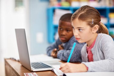 Teknoloji öğrenmek için alanı genişletir. İlkokul çocukları sınıfta çalışırken dizüstü bilgisayar kullanıyorlar.