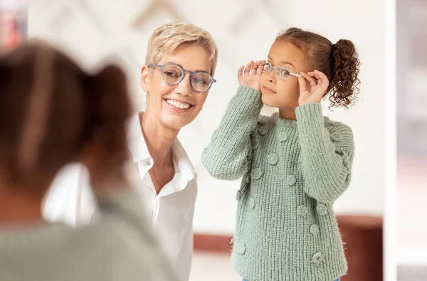 Eyes, consulting and glasses by girl and optometrist woman at optician store for choice, fitting and eye test. Eyesight, eyeglasses and ophthalmologist and child consultation, eye care and vision.