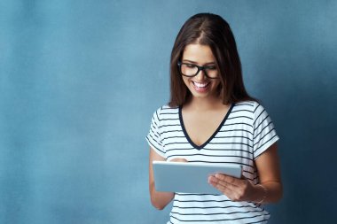 Neredeyse her ihtiyacı karşılayan bir uygulama var. Çekici bir genç kadının, mavi arka planda dijital tablet kullanırken çekilmiş bir fotoğrafı.