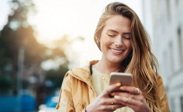 stock image Youll meet so many great people in the city. a young woman using her cellphone while out in the city