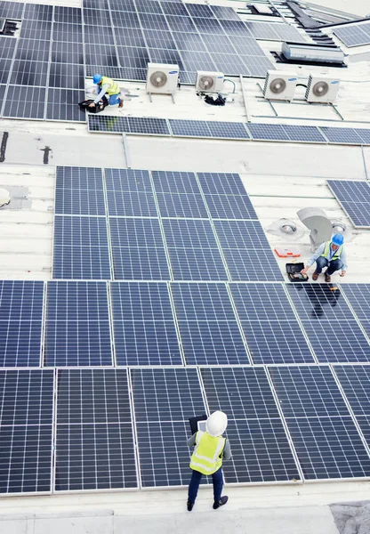 Solar panel, construction and industrial employees on roof for solar energy, engineering and sustainable lifestyle. Building, sustainability and teamwork for clean electricity and photovoltaic power.