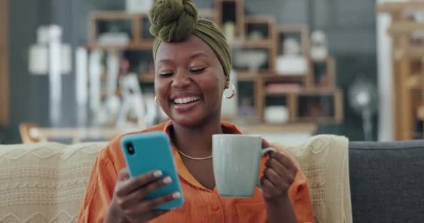 电话和笑着的黑人女人在沙发上的房子或家里的客厅里约会应用程序 喜剧互联网新闻或有趣的迷因 在社交媒体的移动技术上边喝茶边笑笑 — 图库视频影像