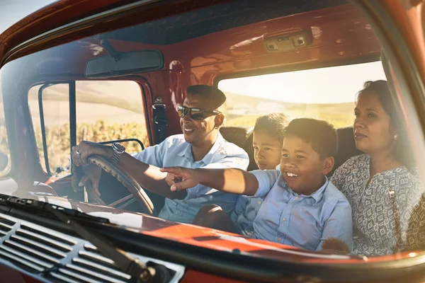 Getting on the road. a cheerful young family driving in a red pickup truck on a rural road outside