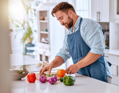 Adam, şef ve yemek pişirme, mutfakta sebze kesme diyet, beslenme ve vitamin ile sağlıklı akşam yemeği veya öğle yemeği hazırlama. Evde önlüklü, organik, taze biberli ve soğanlı yemek.