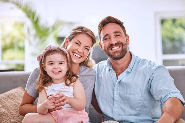 Happy, relax and parents with a child and peace, calm and love on the living room sofa in a house. Smile, bonding and portrait of girl kid with her loving mother and father on the couch in their home.