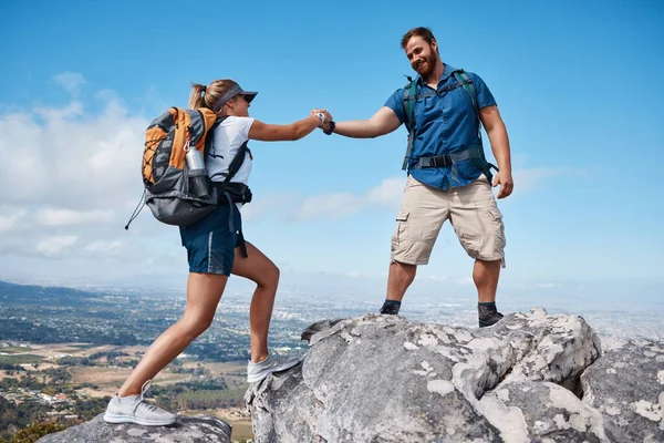Help, couple or friends hiking on mountain in nature with a smile or training. Travel, adventure and trekking workout man and woman on an outdoor, countryside or rock climbing, exercise and support.
