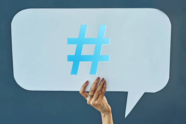 stock image Say it with a hashtag. Cropped studio shot of a woman holding up a speech bubble with a hashtag on it against a gray background