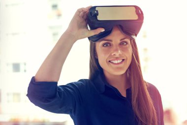 Dünyaya bakış açını değiştir. Ofiste VR kulaklık takan genç bir iş kadınının portresi.