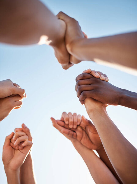 Low angle, group and holding hands in support, trust huddle and motivation for global success, volunteer community or diversity. People, friends or teamwork collaboration in circle for climate change.