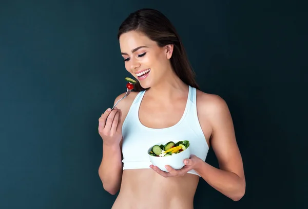 健康的な食べ物だ 暗い背景でサラダを食べる魅力的な若い女性のスタジオショット — ストック写真