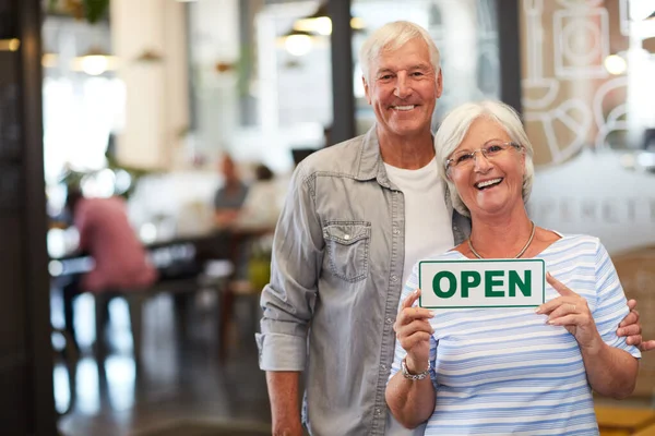 We did it We opened our very own business. Portrait of a happy senior couple holding up an open sign in their store