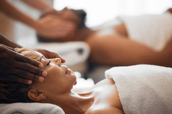 Head massage, spa bed couple and relax on vacation, holiday or retreat with happiness, peace or zen. Black woman, physical therapy salon and lying for care, health or wellness with black man for rest.