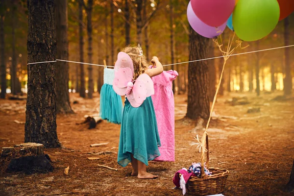 何を着るか決められない 森の中に立っている間にロープの上にドレスをぶら下げている無名の少女 — ストック写真