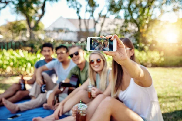 Fotoğraf albümü için bir tane. Genç bir arkadaş grubu yaz güneşinde dışarıda birkaç içki içerken selfie çekiyor.