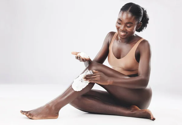 黒の女性は 笑顔でスキンケア 化粧品や肌の健康のための足の上にシェービングクリームと座って 幸せなアフリカ人女性 身体毛やセルフケア スタジオの背景による自己愛と健康 — ストック写真