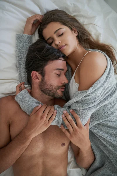 没有人能幸免于拥抱 一对快乐的年轻夫妇在床上依偎在一起拍的高角镜头 — 图库照片
