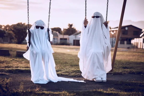 怖いファンタジーの休日を祝う子供の遊び場で幽霊の衣装の公園 ハロウィーン 不気味なクレイジーカップルで恐怖 創造的で不気味な白いシーツオンザスイング — ストック写真