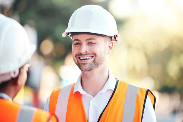 Safety, architecture and happy engineer at a construction site talking or speaking at a home renovation. Smile, contractor and engineering partner in conversation at an outdoor building project job.