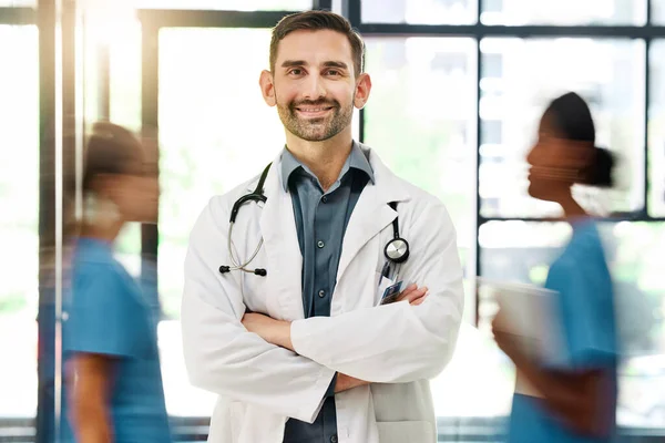 Doctor, hospital and medical insurance with stethoscope and healthcare worker happy about career choice, service or care. Portrait of male medicine or cardiology expert with busy staff for emergency.