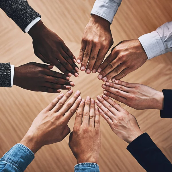 Every contribution counts. High angle shot of a group of unidentifiable businesspeople joining their hands together in a unity