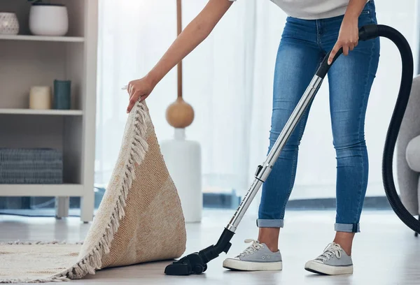 Woman, cleaning and doing house work with vacuum machine appliance for living room carpet to clean dirt or dust. Feet of female cleaner or housewife doing housekeeping on lounge floor for hygiene.
