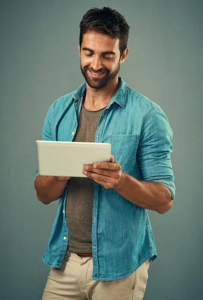 stock image Checking out the latest online. Studio shot of a handsome young man using a digital tablet against a grey background