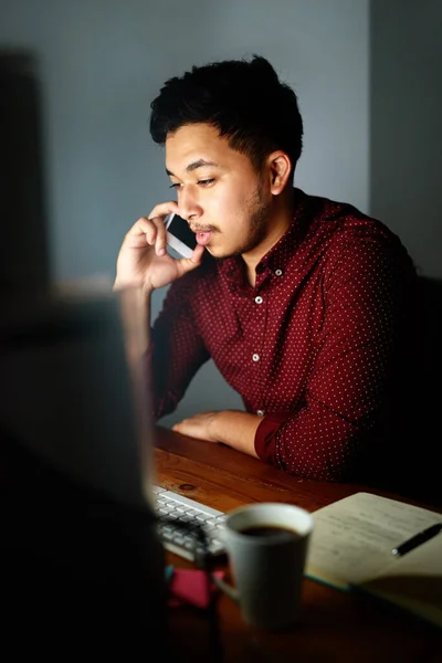 あと数時間でここに来る 若い男性デザイナーが電話で話をし 夜遅くに彼のコンピュータで作業する — ストック写真