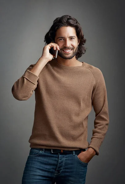 Call me. Id love to hear from you. Studio shot of a handsome young man using a mobile phone to make a call against a gray background