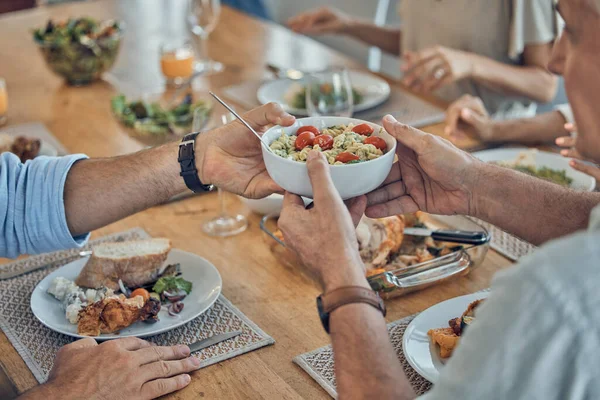 Hands, food and family with a group of people gathered around a dining room table for a meal or feast at home. Salad, buffet and celebration with relatives eating lunch or supper together in a house.