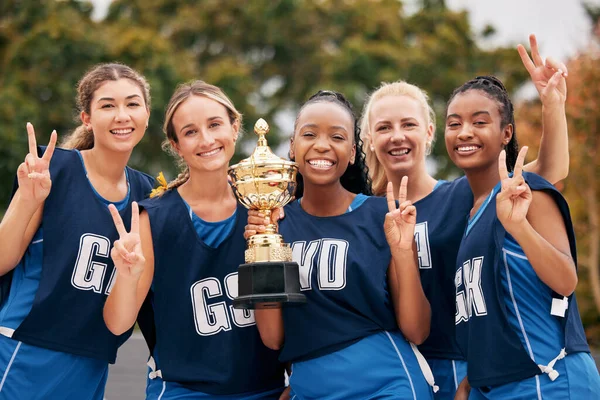 Sports, netball and trophy with a woman team in celebration as a winner group of a victory or achievement. Peace, winning and teamwork with a female sport group celebrating success with a cup.