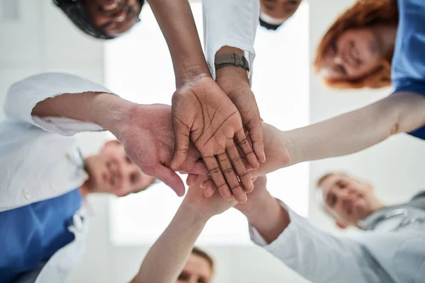 Working together to uphold their quality standard of healthcare. Low angle shot of a group of medical practitioners joining their hands together in unity