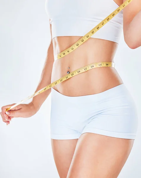 グレーの背景にスタジオで体重減少を追跡するために彼女の腰を測定する女性とのボディ テープ測定と食事 フィットネス 健康と健康若い女性が体重を減らすための彼女の食事療法を指導 — ストック写真