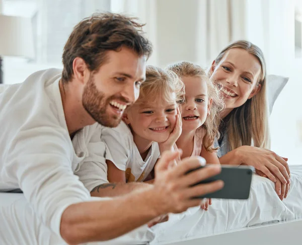 一个快乐的家庭 一个自私自利的人 一个聪明的人 早上一起在家里为爱 照顾或放松而在卧室里 微笑的父母 兴奋的孩子和手机 数码照片 快乐的生活方式 — 图库照片
