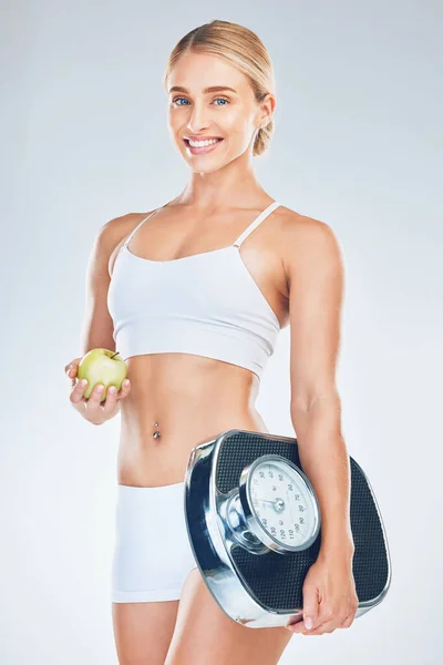 グレースタジオの背景に体重を減らすためにリンゴを持つ女性の規模 笑顔と肖像画 栄養と訓練の動機と健康のための果物やスケールと幸せな若いモデル — ストック写真