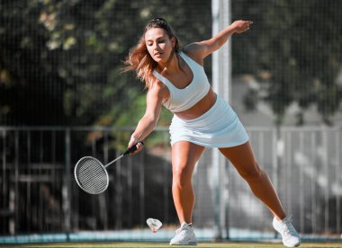 Badminton, spor ve kadın sporcu raketi ile açık hava sporlarında sallanmaya hazır. Genç bayan oyuncu kardiyo egzersizi yapıyor, maç antrenmanı yapıyor ve sağlık mahkemesinde sağlık eğitimi alıyor..