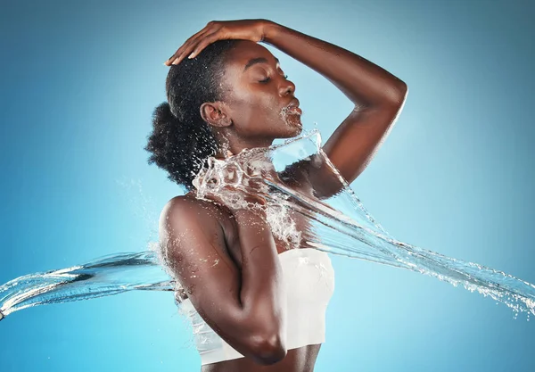 健康とボディクリーニングのための水スプラッシュ 黒の女性とスキンケアの健康シャワー アフリカ系アメリカ人の女の子 青の背景スタジオで豪華な皮膚科のライフスタイルとボディケア — ストック写真