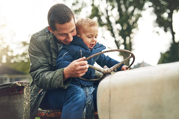 stock image Hold on tight. a father and his little son playing together on a farm tractor outside