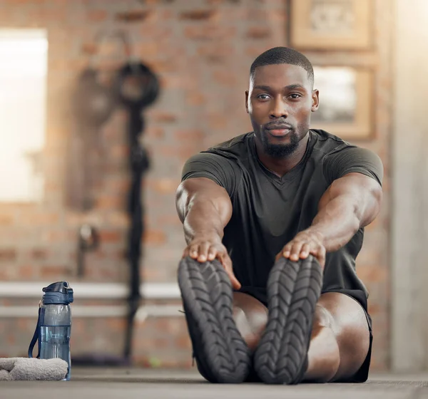Black man, stretching and fitness in gym workout, training and exercise with health goals, motivation or wellness target. Bodybuilder, sports athlete or personal trainer in warmup for muscle relief.