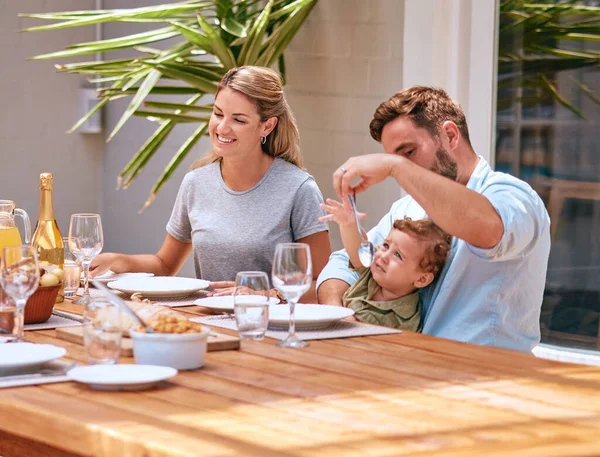 Food, mother and father with baby at table at an outdoor patio for holiday celebration with champagne and lunch in summer. Happy family, mom and dad with child fine dining together at home or house.