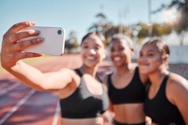 Spor, kadınlar ve koşucu grubuyla spor, antrenman ve açık hava sporları için koşu pistinde selfie. Arkadaşlar, telefon ve kız atlet takımı, gülümseyin ve egzersiz için stadyumda fotoğraf çekin..