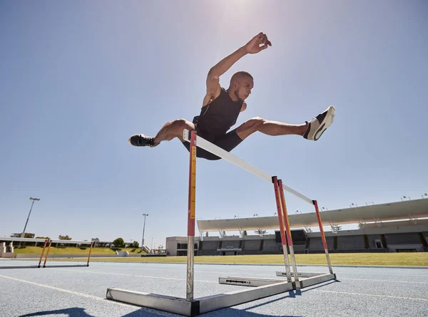 Running, jump and athlete hurdle for a speed exercise, marathon or runner training in a stadium. Short health, cardio and man run fast for a jumping competition or fitness workout for sports wellness.