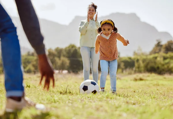 Parents, park and girl kick soccer ball for fun sports learning, bonding and relax in sunshine, garden and nature together. Happy family, little girl and black people playing football on grass field.